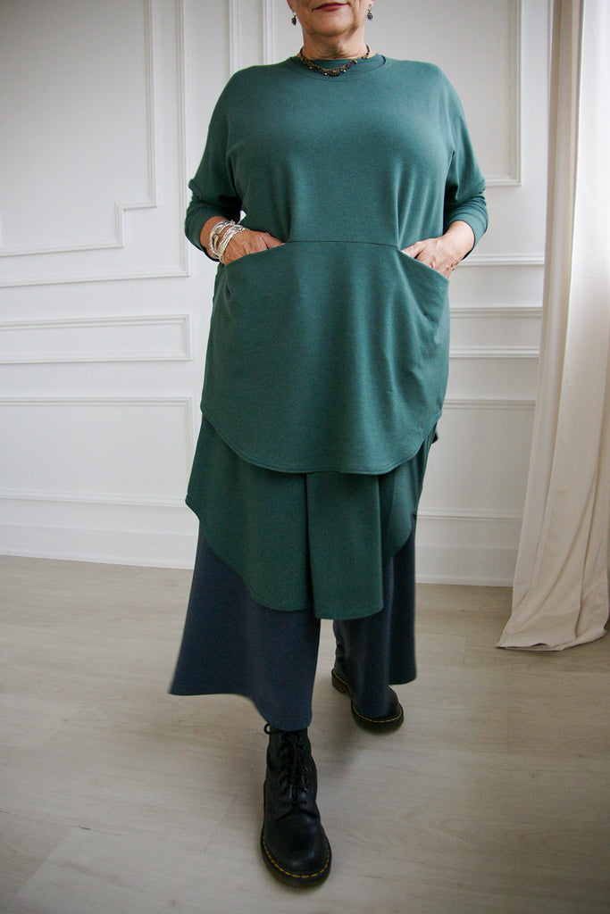 Woman wearing pine green tencel long sleeve Anaella top over long sleeve shirt and wide pants, by Advika. 